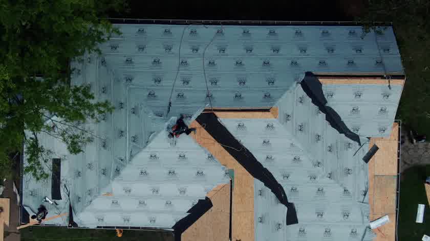 Peel-and-stick underlayment being installed across a roof deck